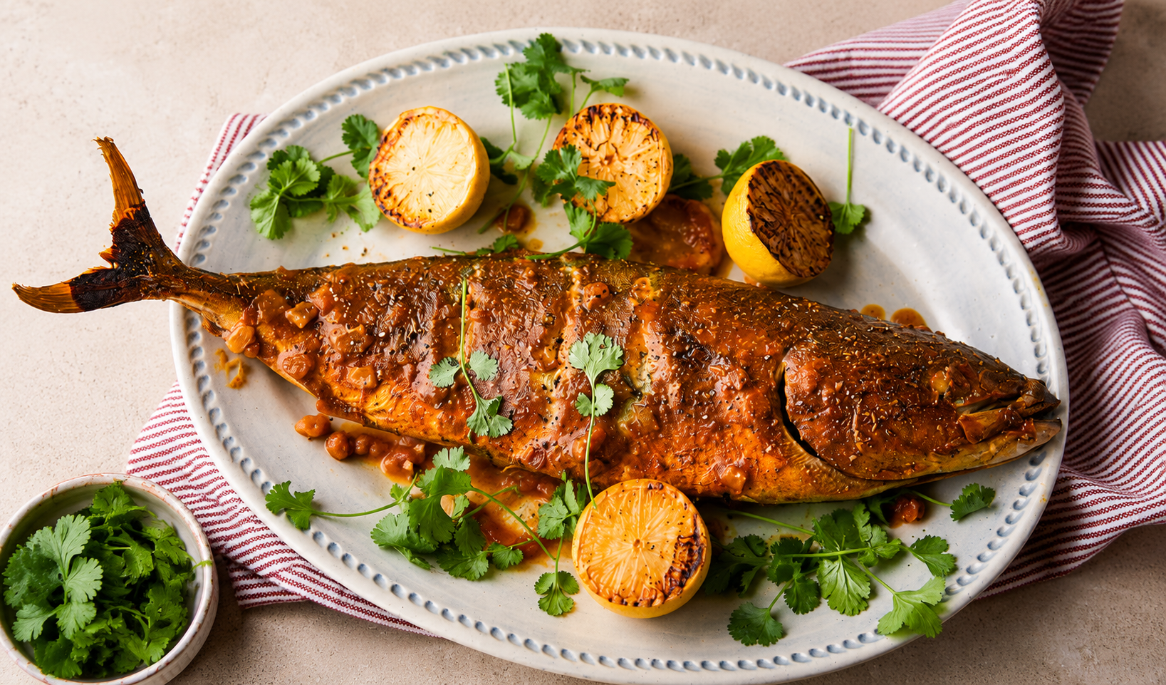 Whole grilled tilapia in red pepper sauce with charred lemon and fresh coriander