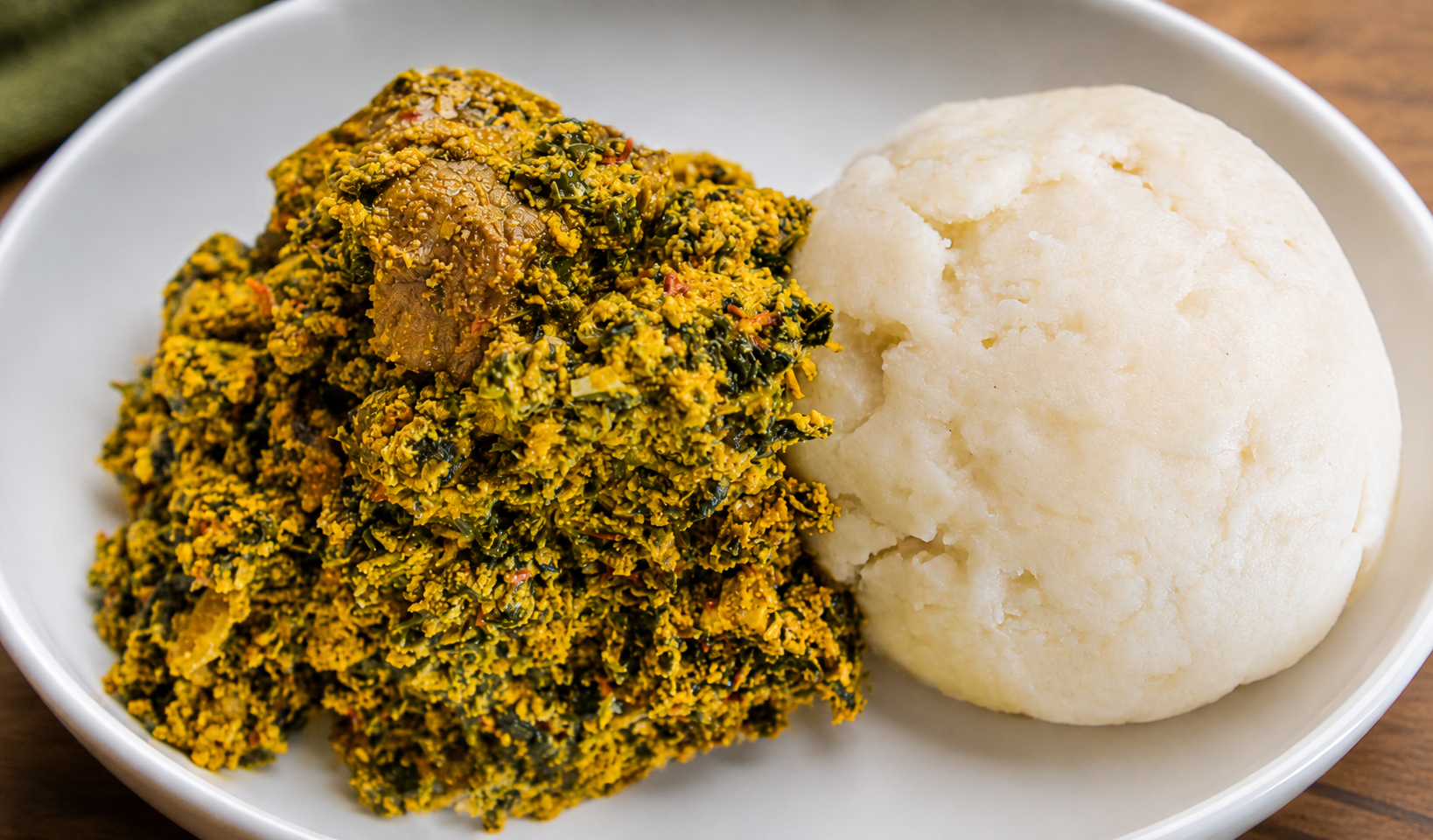 Egusi soup with assorted meat and greens served with smooth white pounded yam